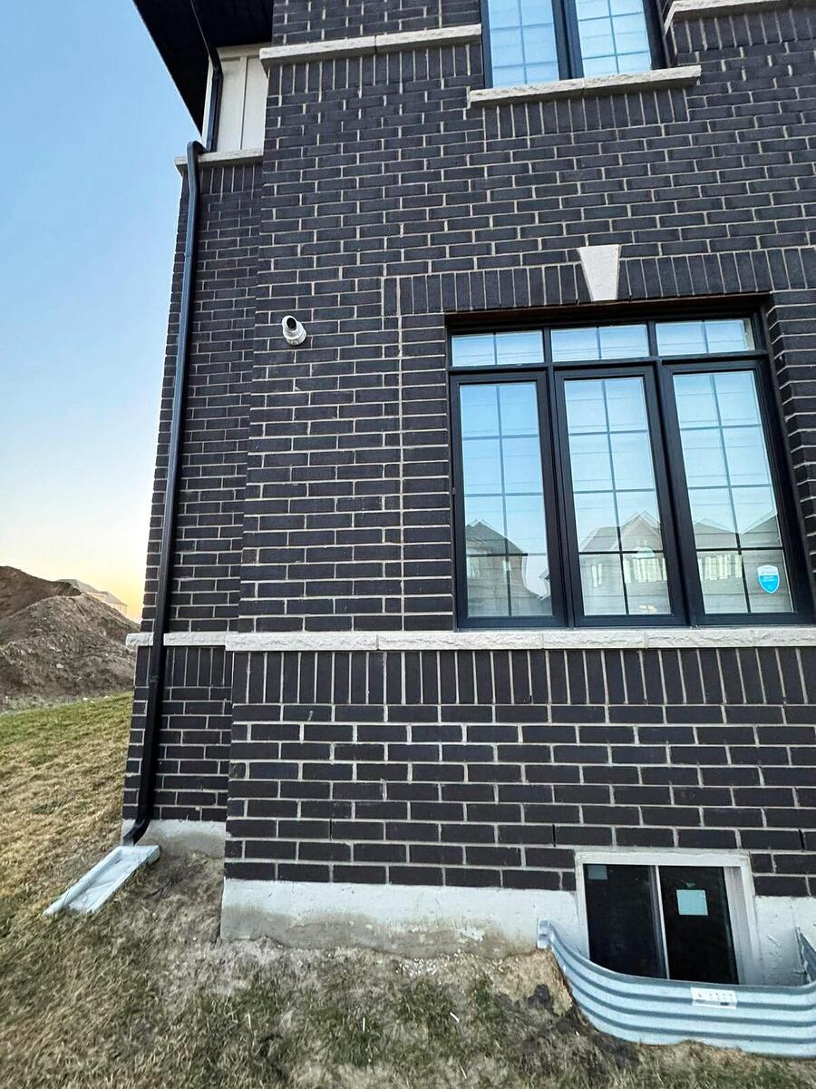 Security camera installed on the brick exterior of a new build home at sunset