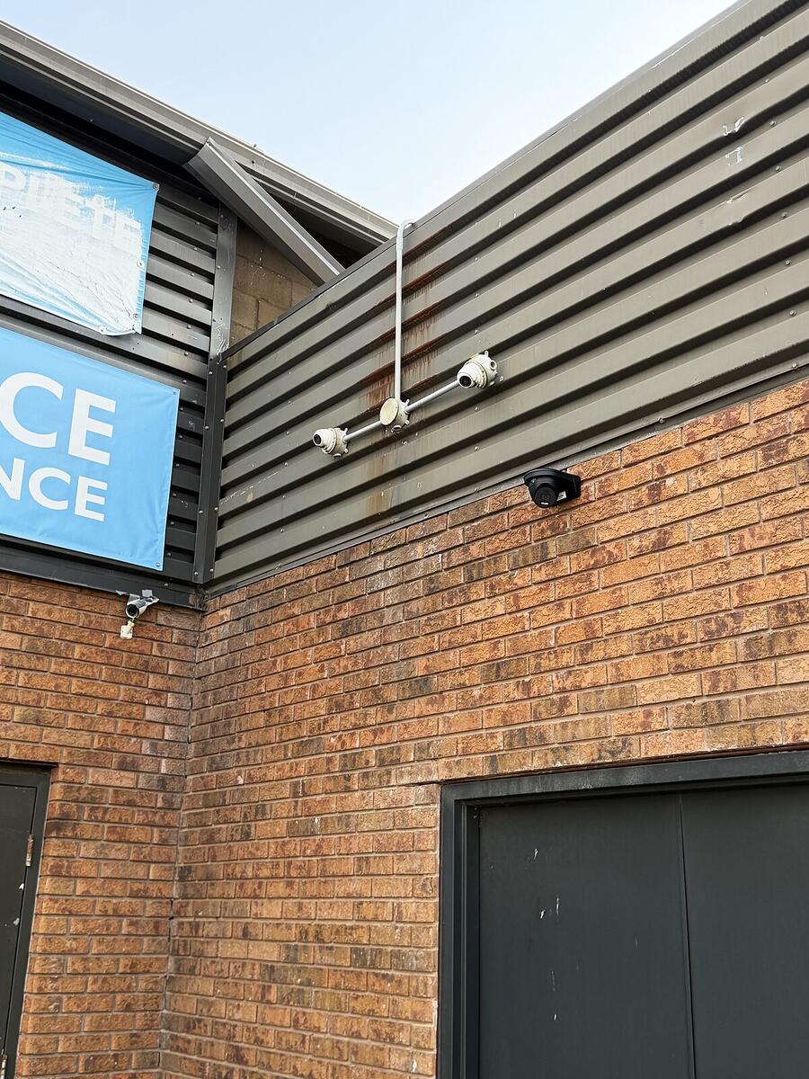 New camera installed alongside older equipment on a commercial building exterior