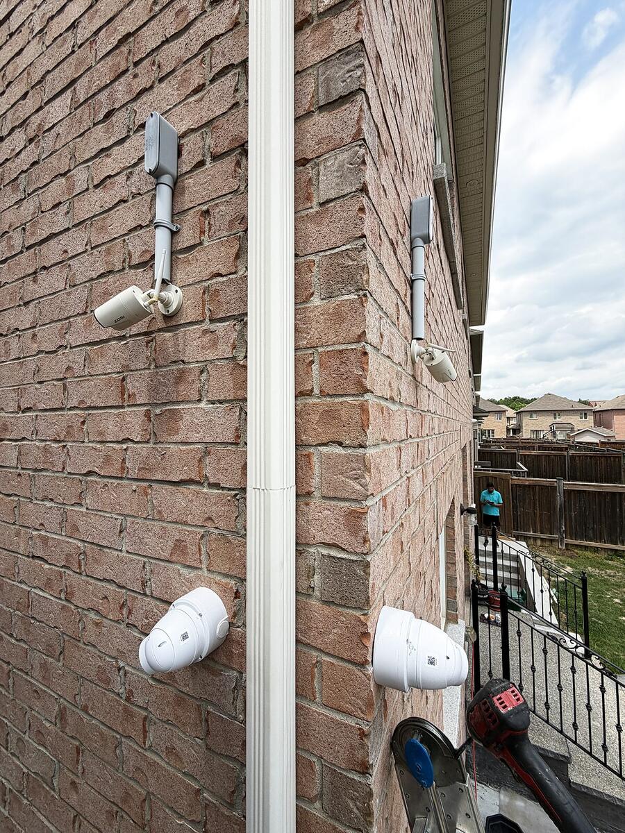 Four cameras installed around a residential corner with tidy conduit and junction boxes