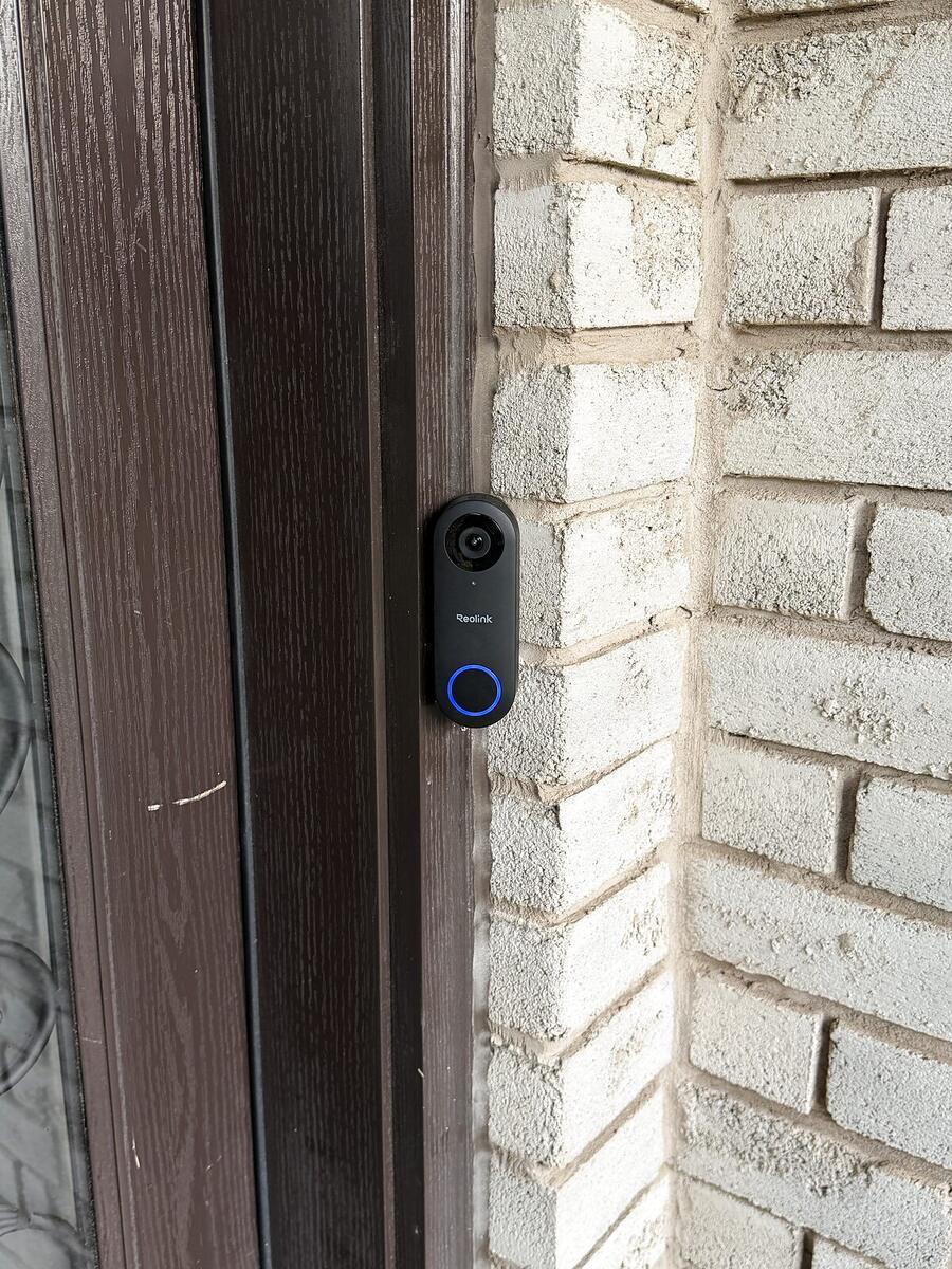 Video doorbell installed beside a front door on brick